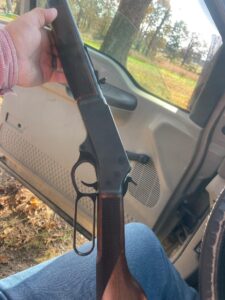 Hand holding a rifle inside a vehicle.