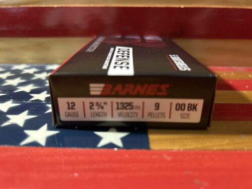 Barnes 12-gauge shotgun ammunition box on flag background.