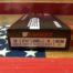 Barnes 12-gauge shotgun ammunition box on flag background.