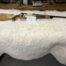 Custom wooden rifle displayed on white furry blanket.