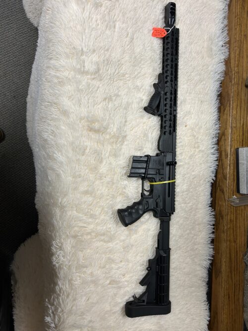 Black rifle on white furry surface.