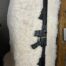 Black rifle on white furry surface.