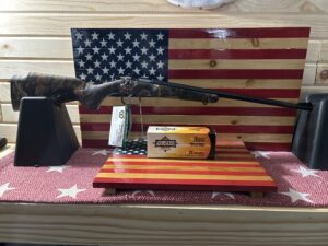 Rifle and ammo box on American flag backdrop.