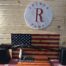 Rifle displayed on American flag backdrop in pawn shop.