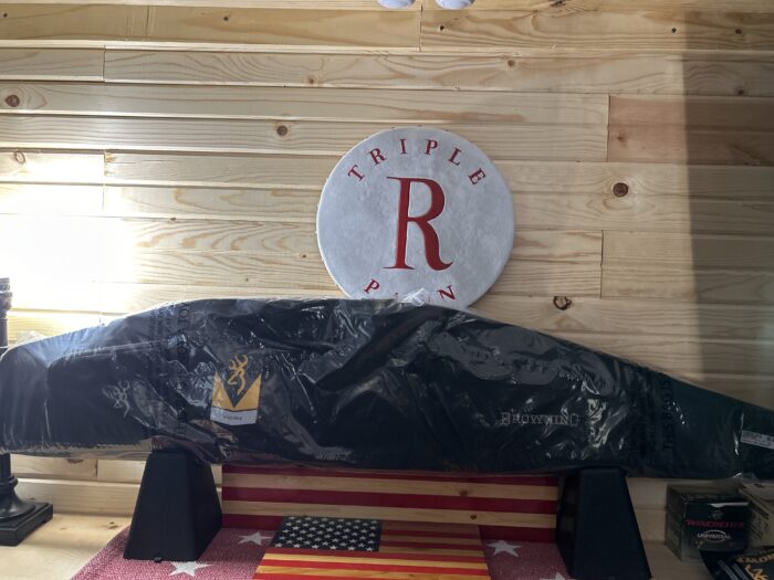 Triple R bar logo on wooden wall, rifle case.