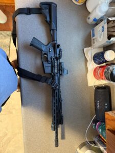 Black rifle on gray countertop near speaker