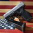 Taurus G2C pistol with magazine on flag background.