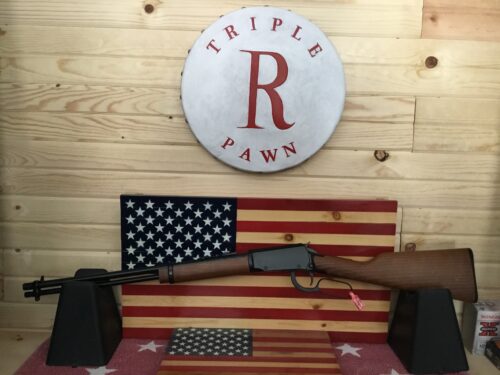 Lever action rifle displayed with American flag backdrop.