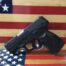 Black handgun against American flag background.