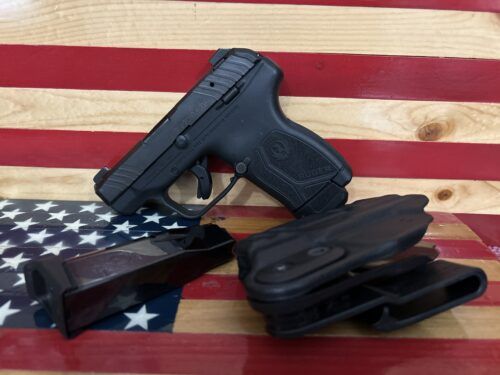 Ruger pistol with magazine and holster on flag background.
