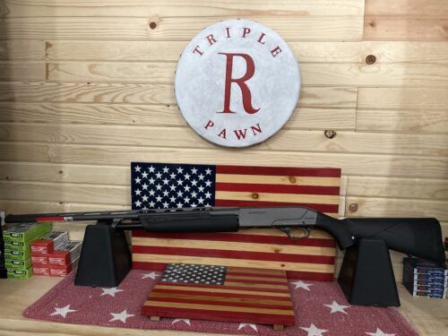 Shotgun displayed with American flag backdrop at pawnshop.