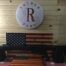Shotgun displayed on American flag backdrop at shop.