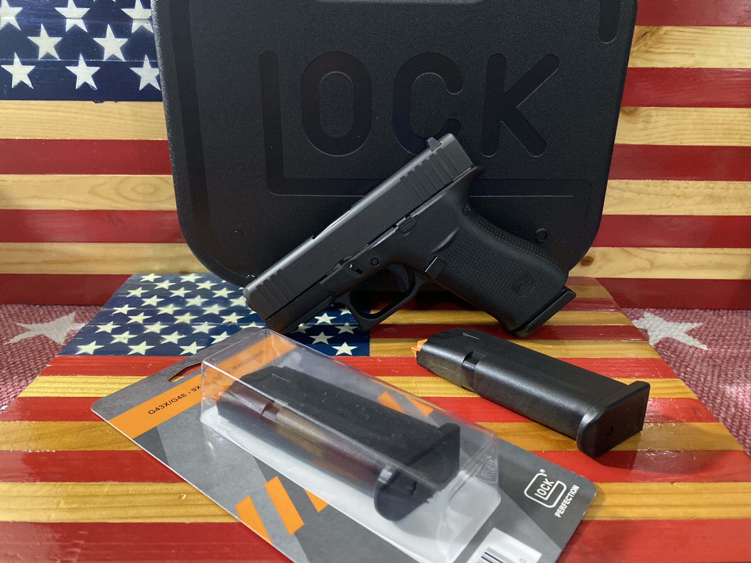 Handgun with case and accessories on flag background.