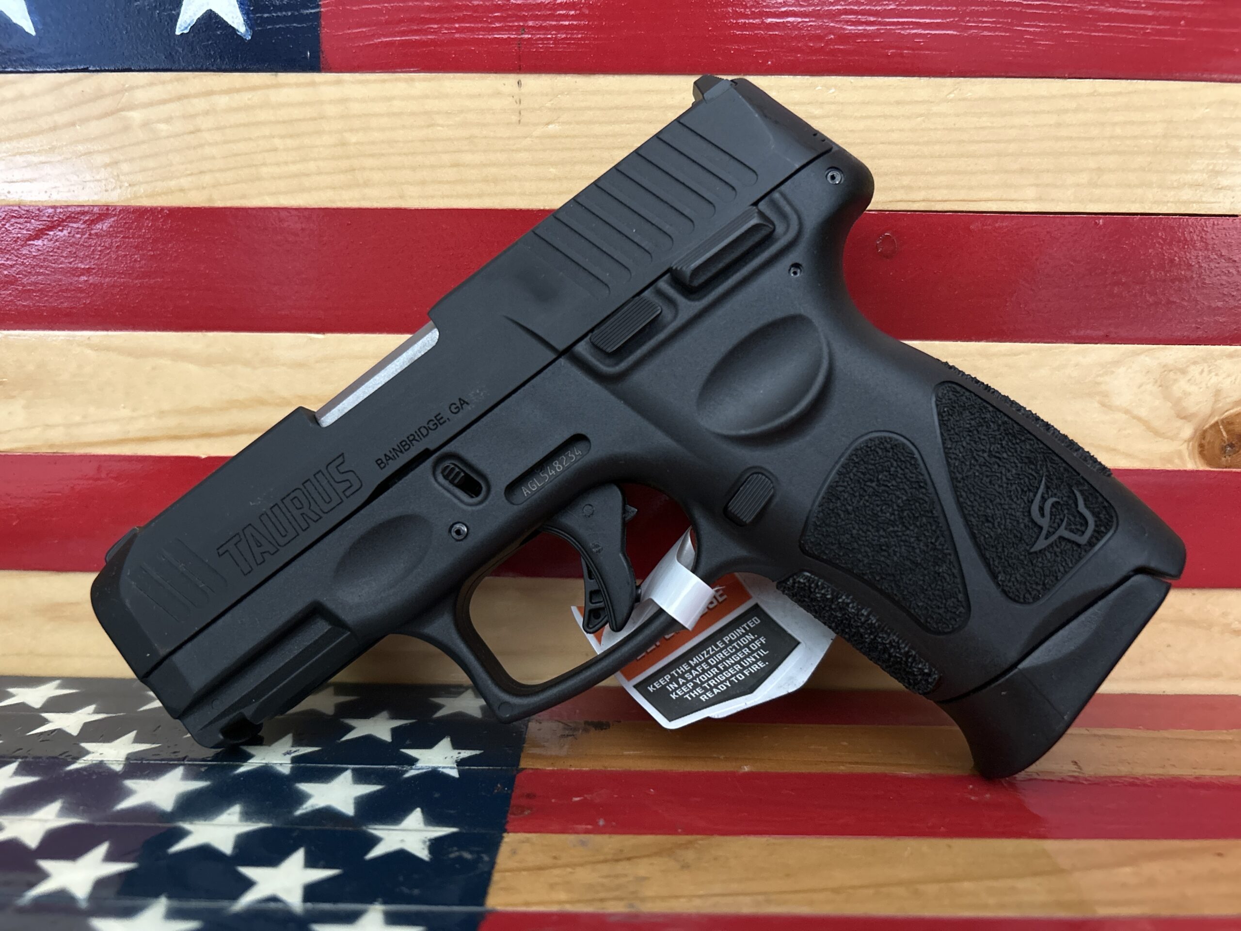 Black Taurus pistol on American flag background.