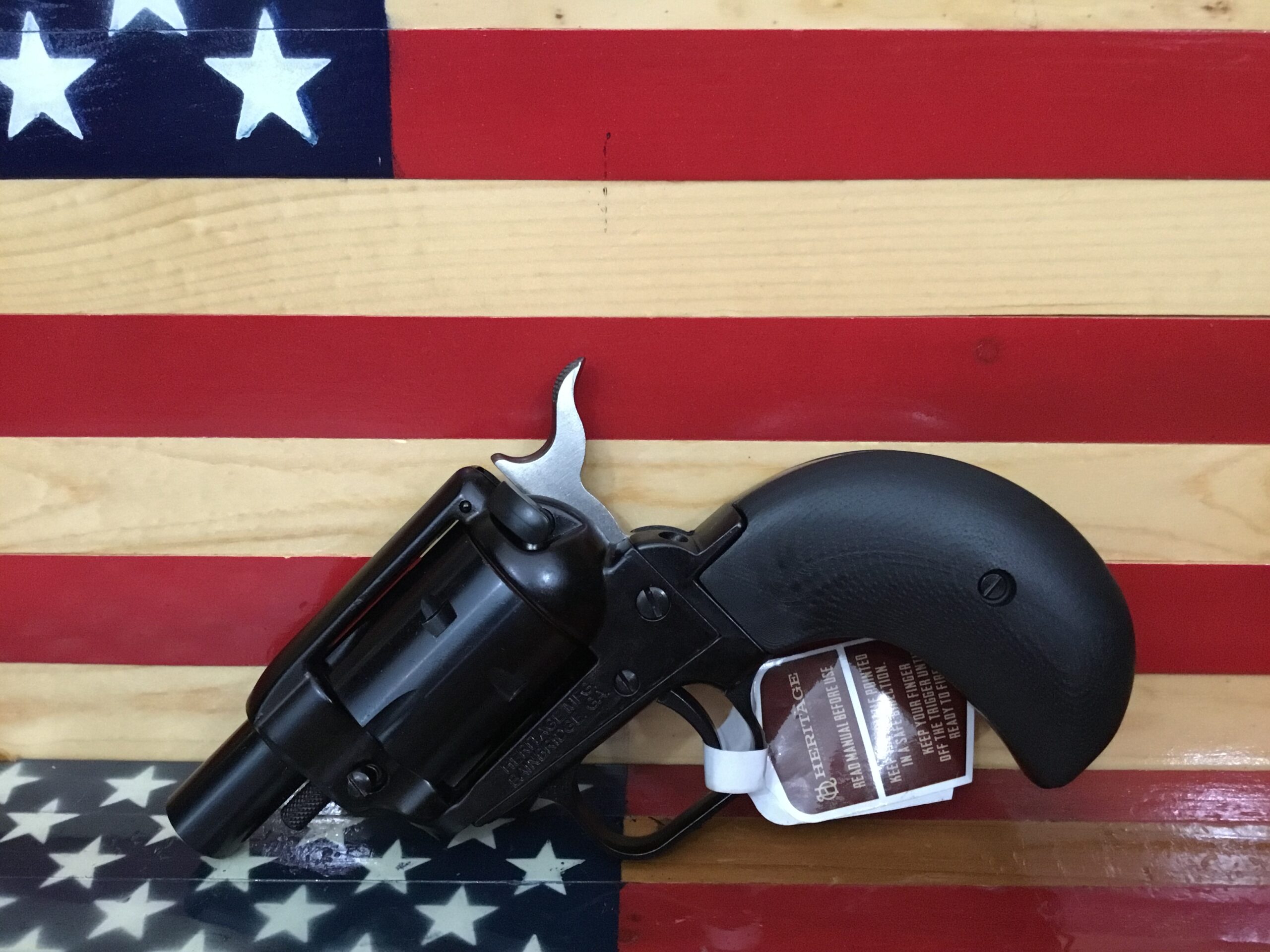 Black revolver on wooden American flag background.