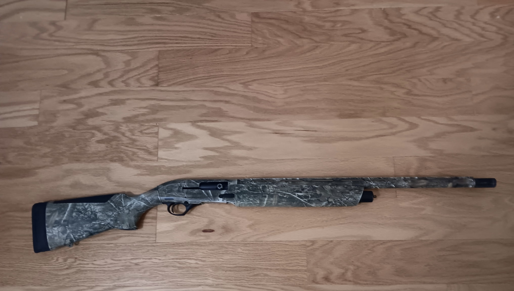 Camouflage shotgun on wooden floor