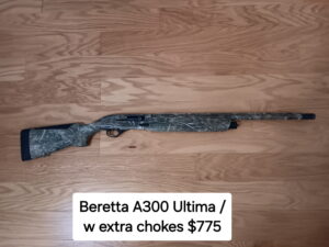 Camouflage shotgun on wooden floor.