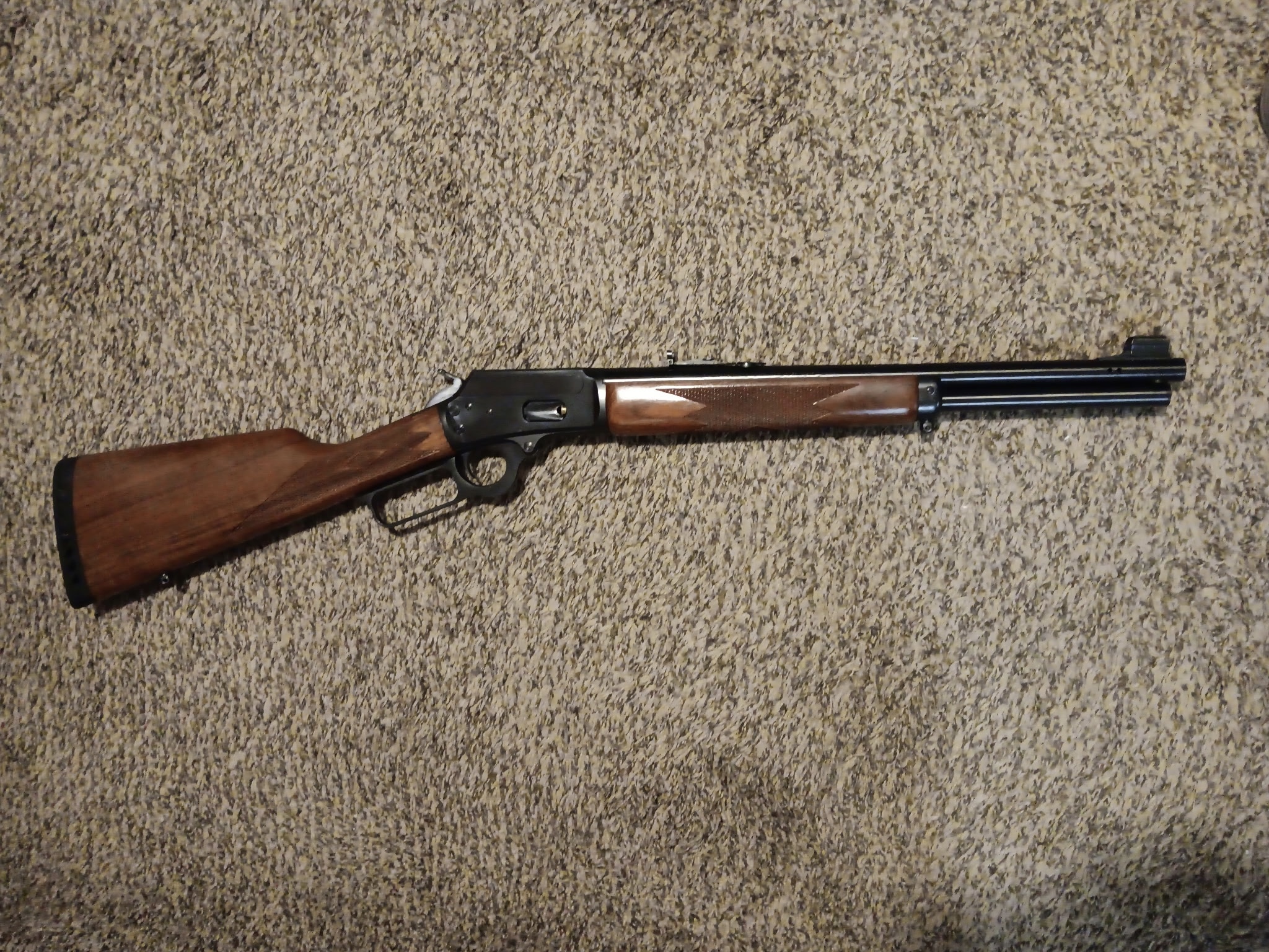 Lever-action rifle on textured carpet background.