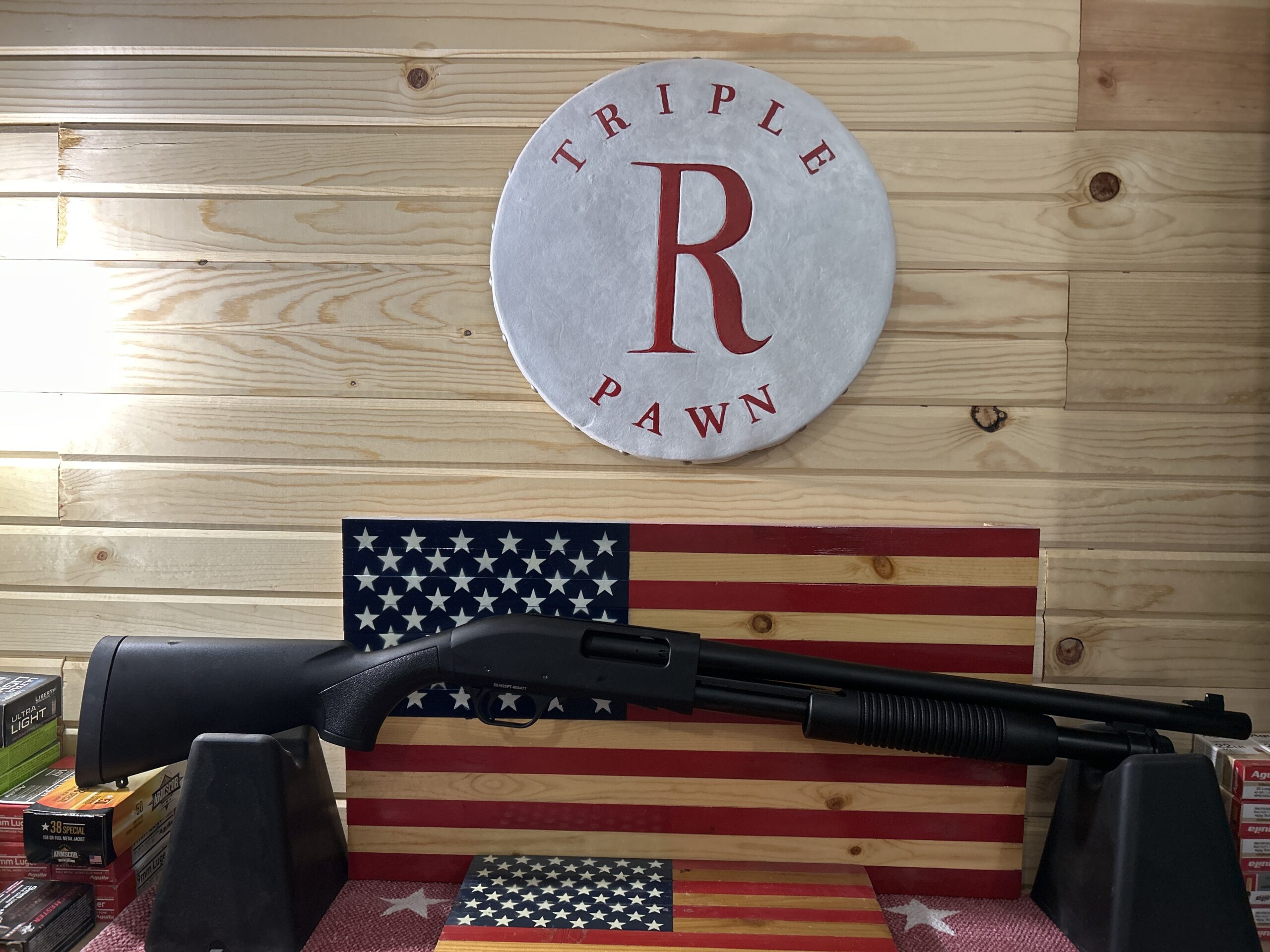 Shotgun displayed with American flag backdrop.