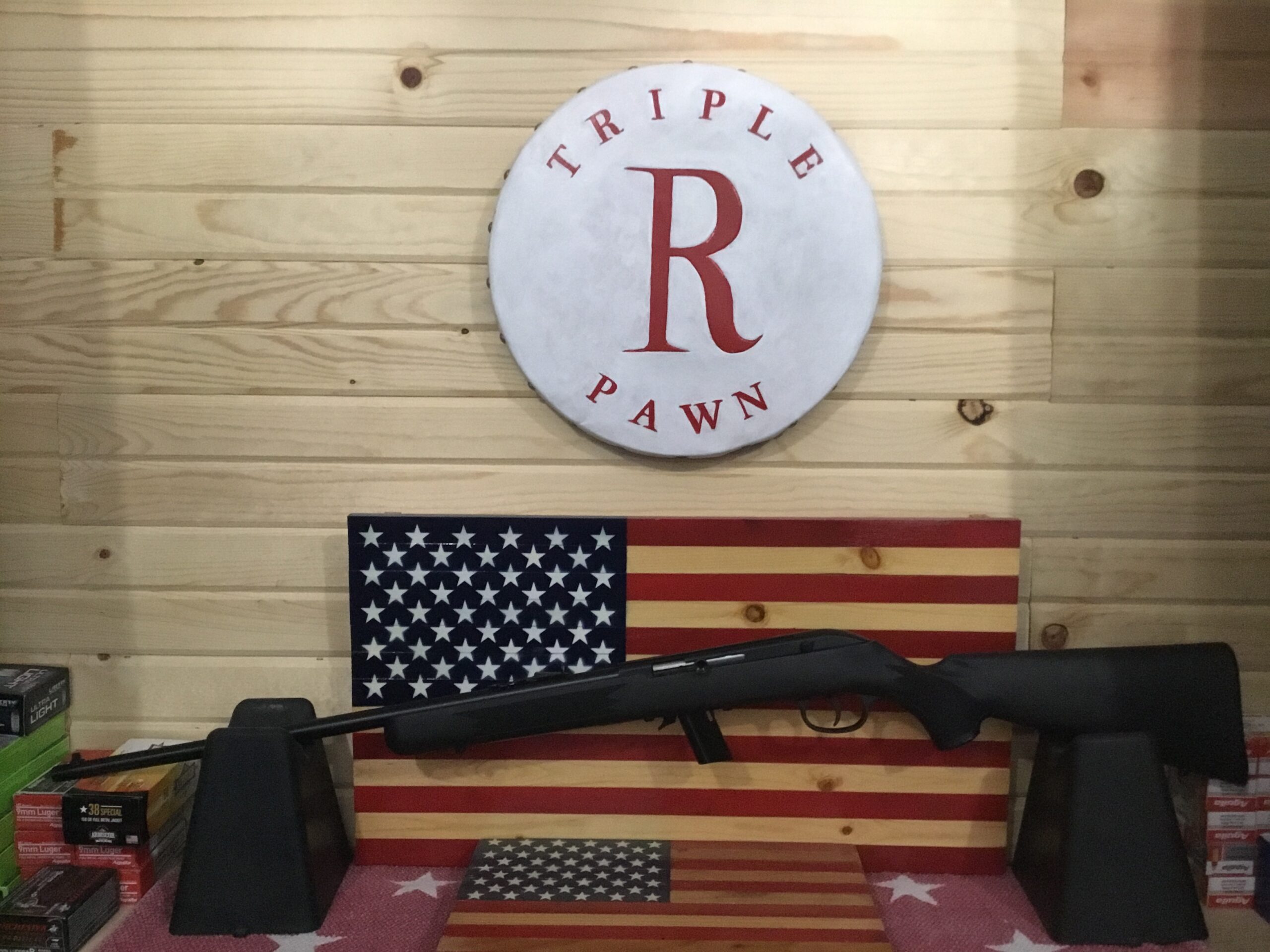 Rifle displayed on American flag background in store.