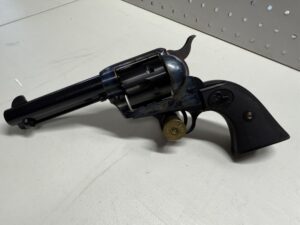 Colt revolver with cartridge on display table.
