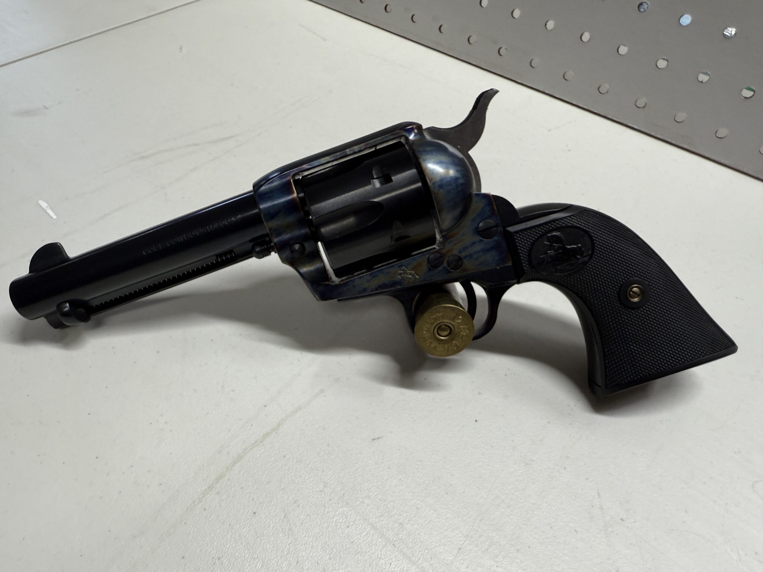 Colt revolver with cartridge on display table.