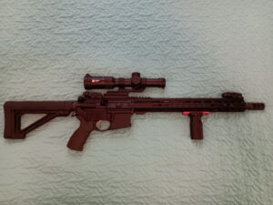 Modern rifle with scope on a quilted background.