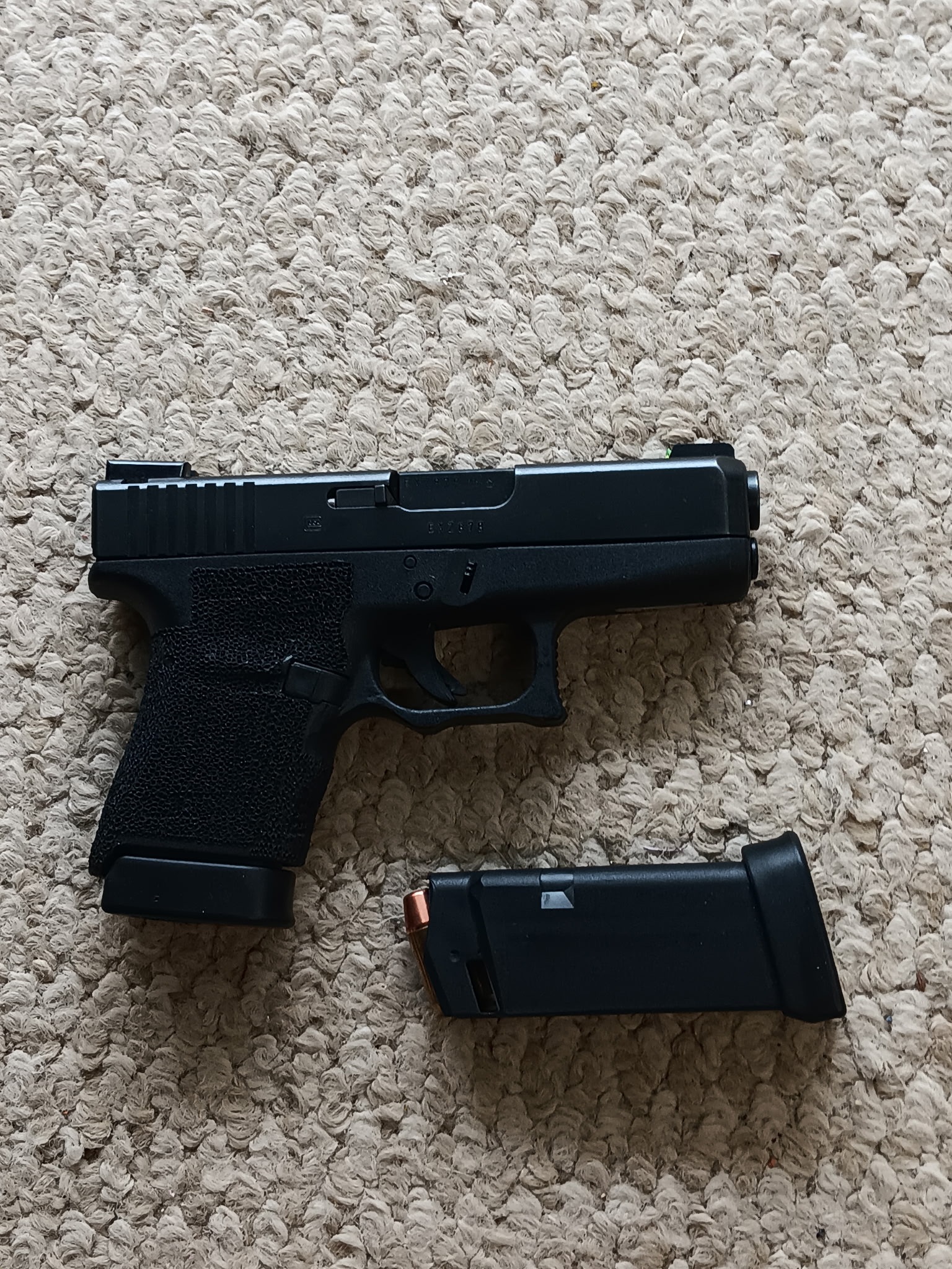 Black handgun and magazine on carpet
