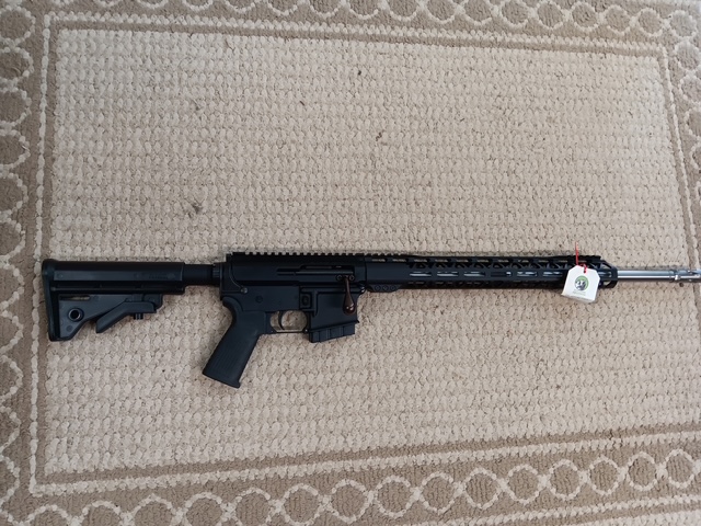 Black rifle on a patterned carpet background.