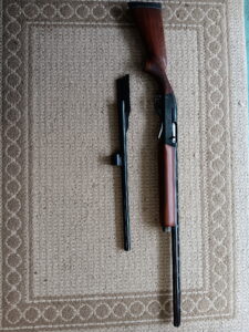 Disassembled shotgun on textured carpet background.