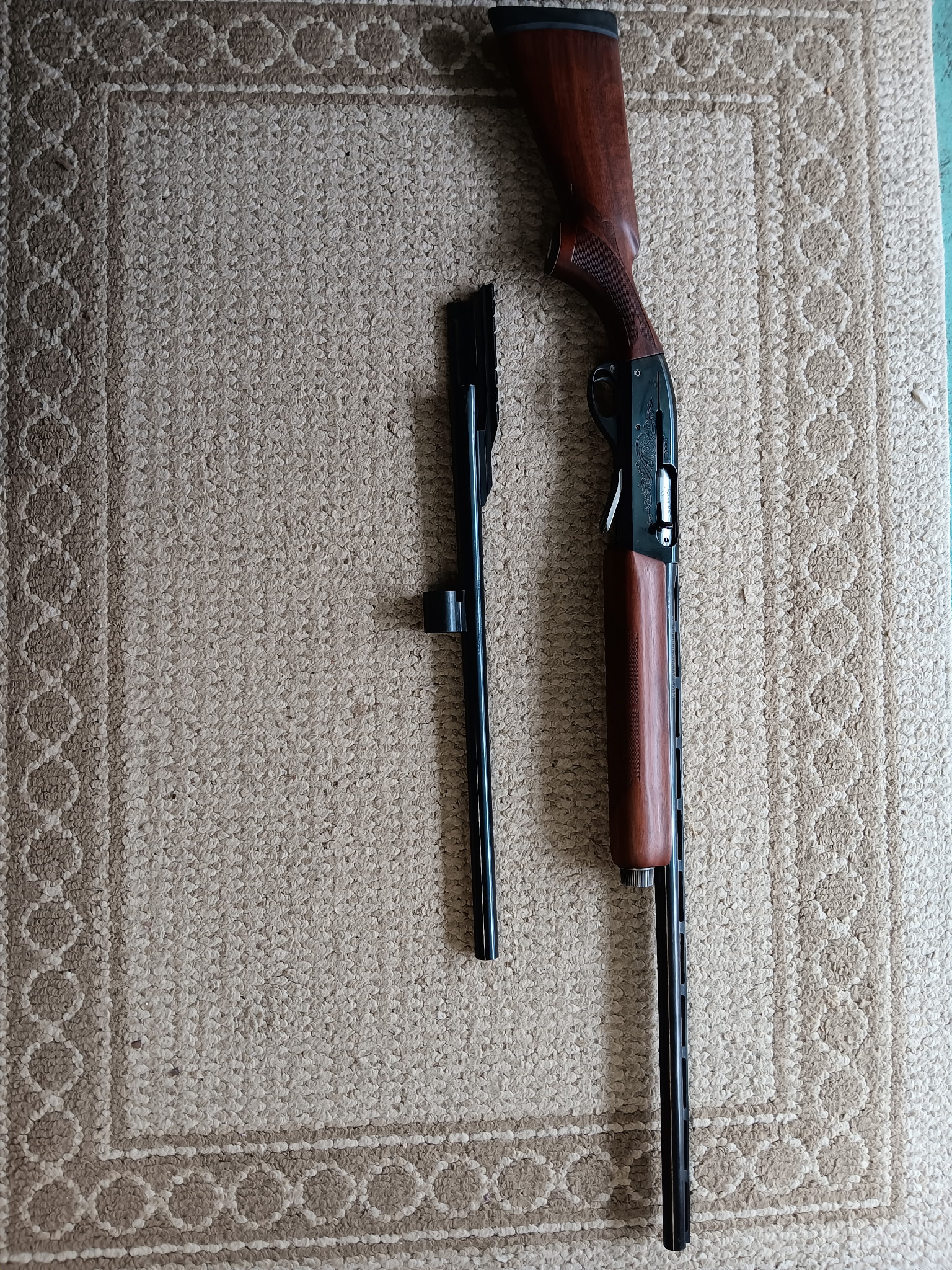 Disassembled shotgun on textured carpet background.