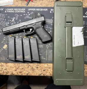 Handgun with magazines and ammunition box on table.
