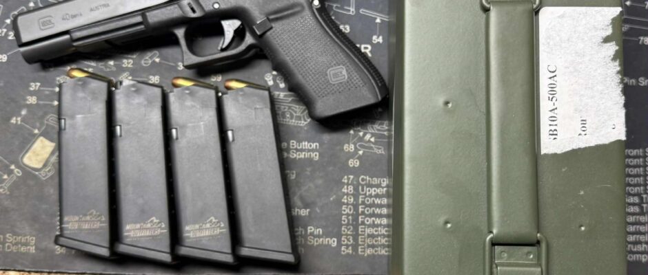 Handgun with magazines and ammunition box on table.