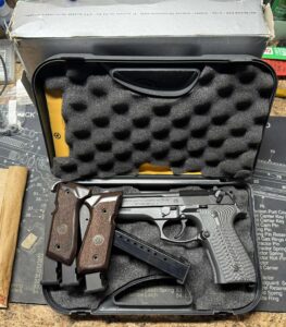 Handgun with wooden grips and magazines in a case.