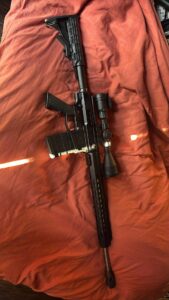 Rifle with scope on orange fabric background.