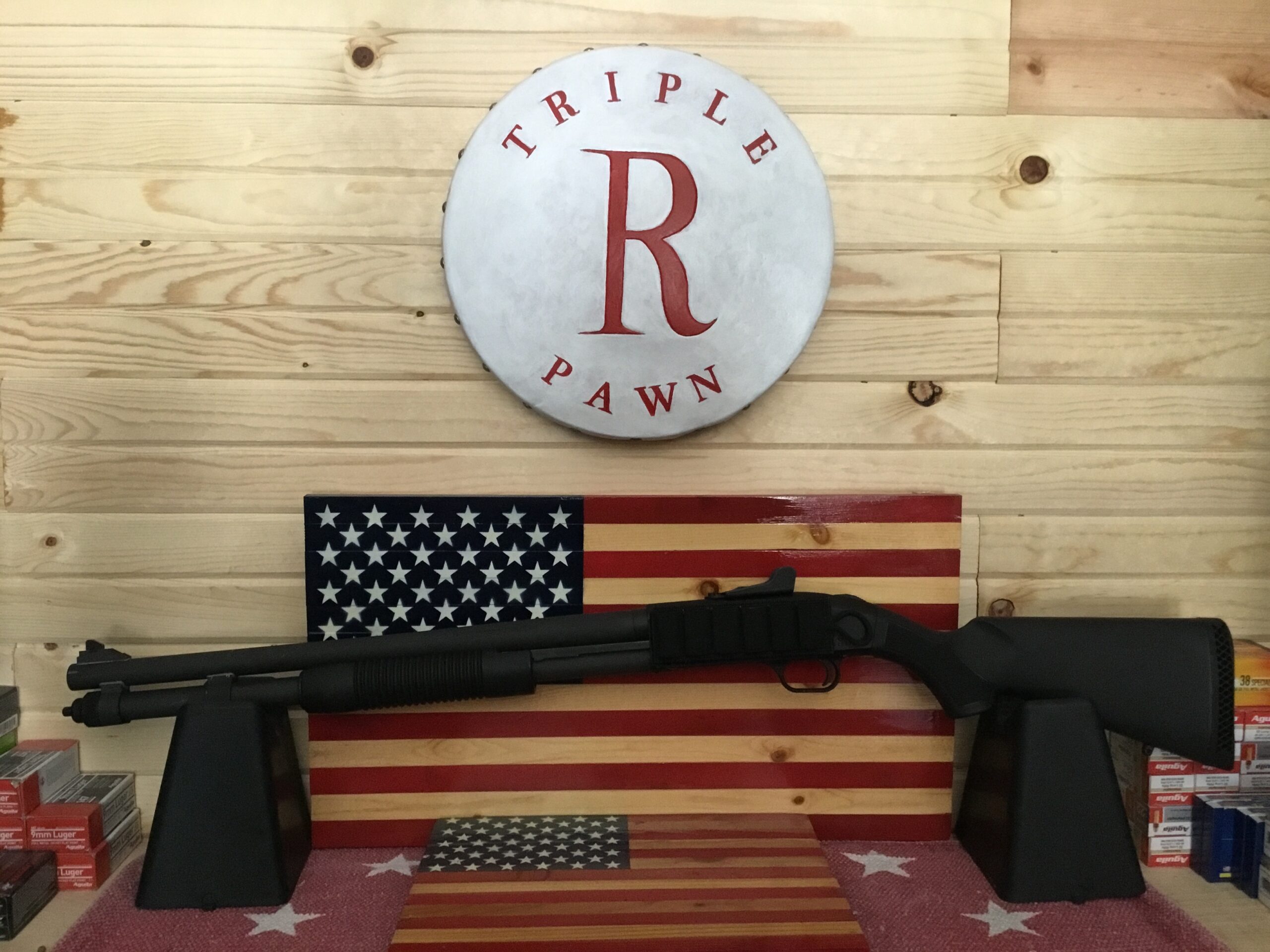 Shotgun displayed with American flag backdrop.