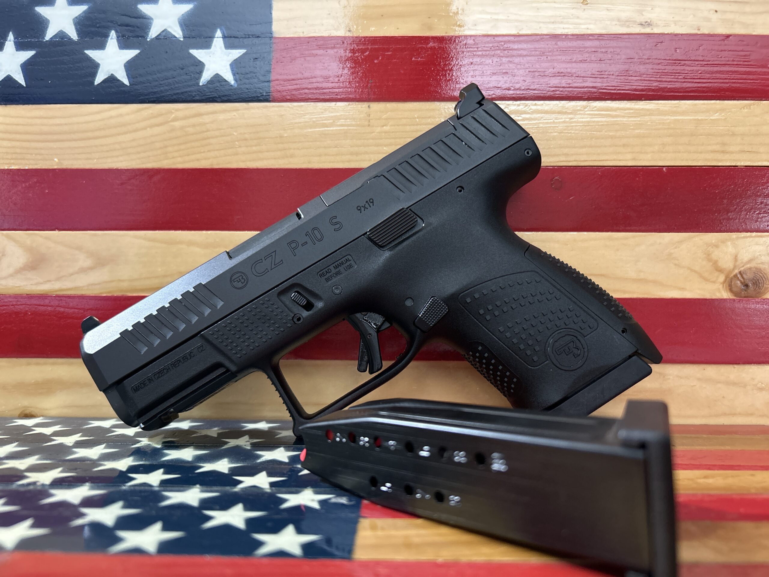 Black handgun with magazine on American flag background.