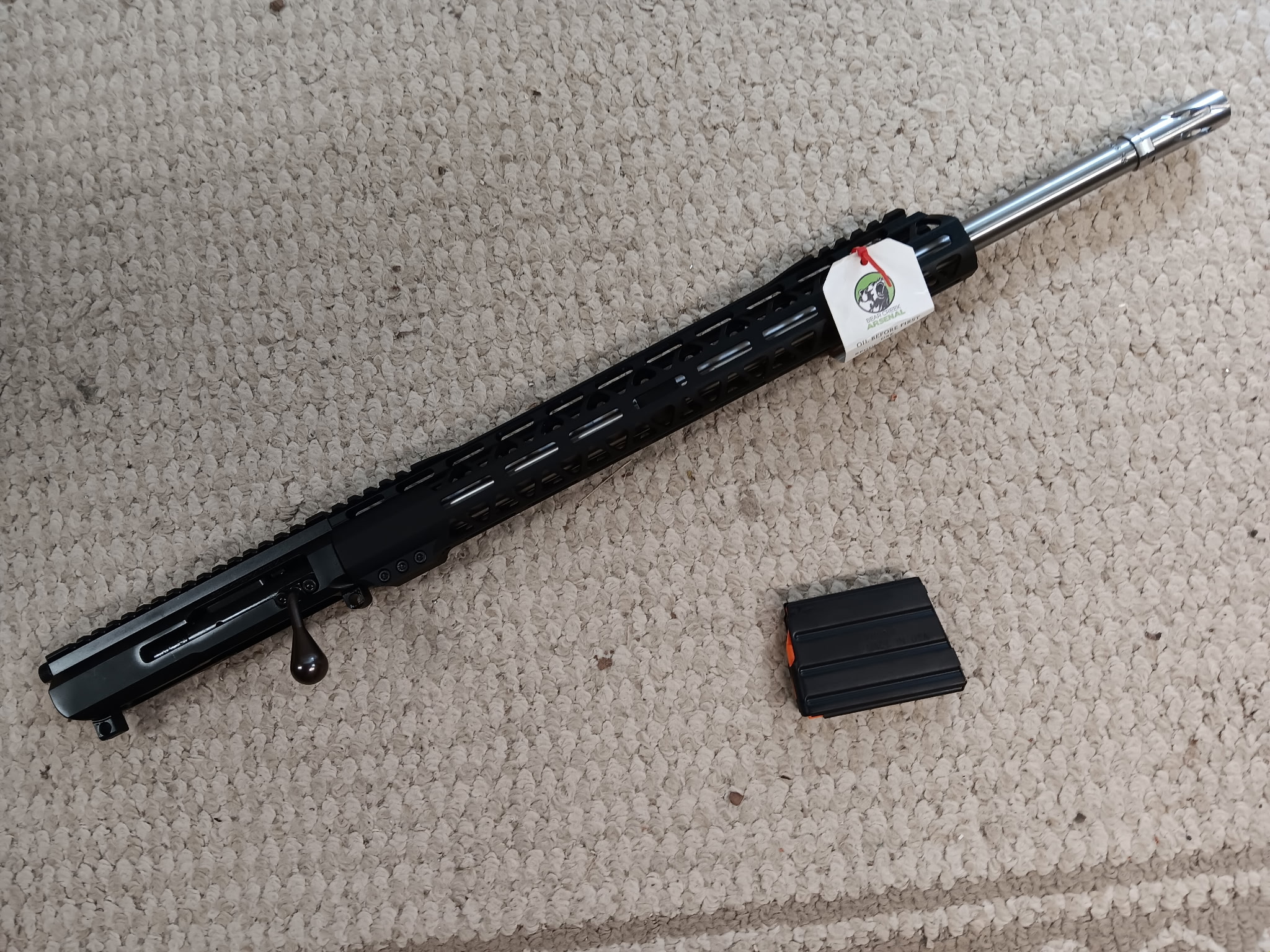 Black rifle barrel with magazine on carpet.