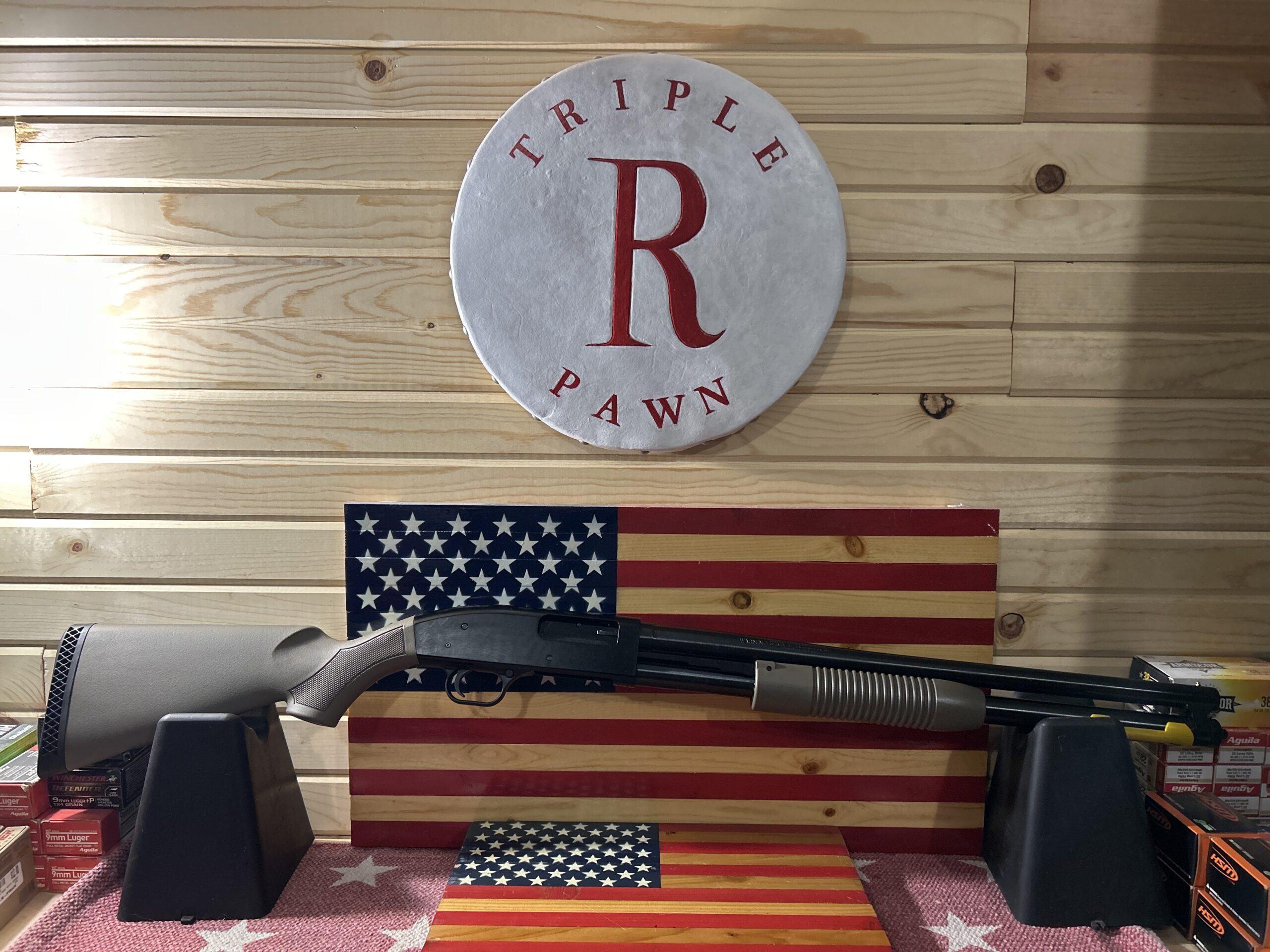 Shotgun on display with American flag backdrop.